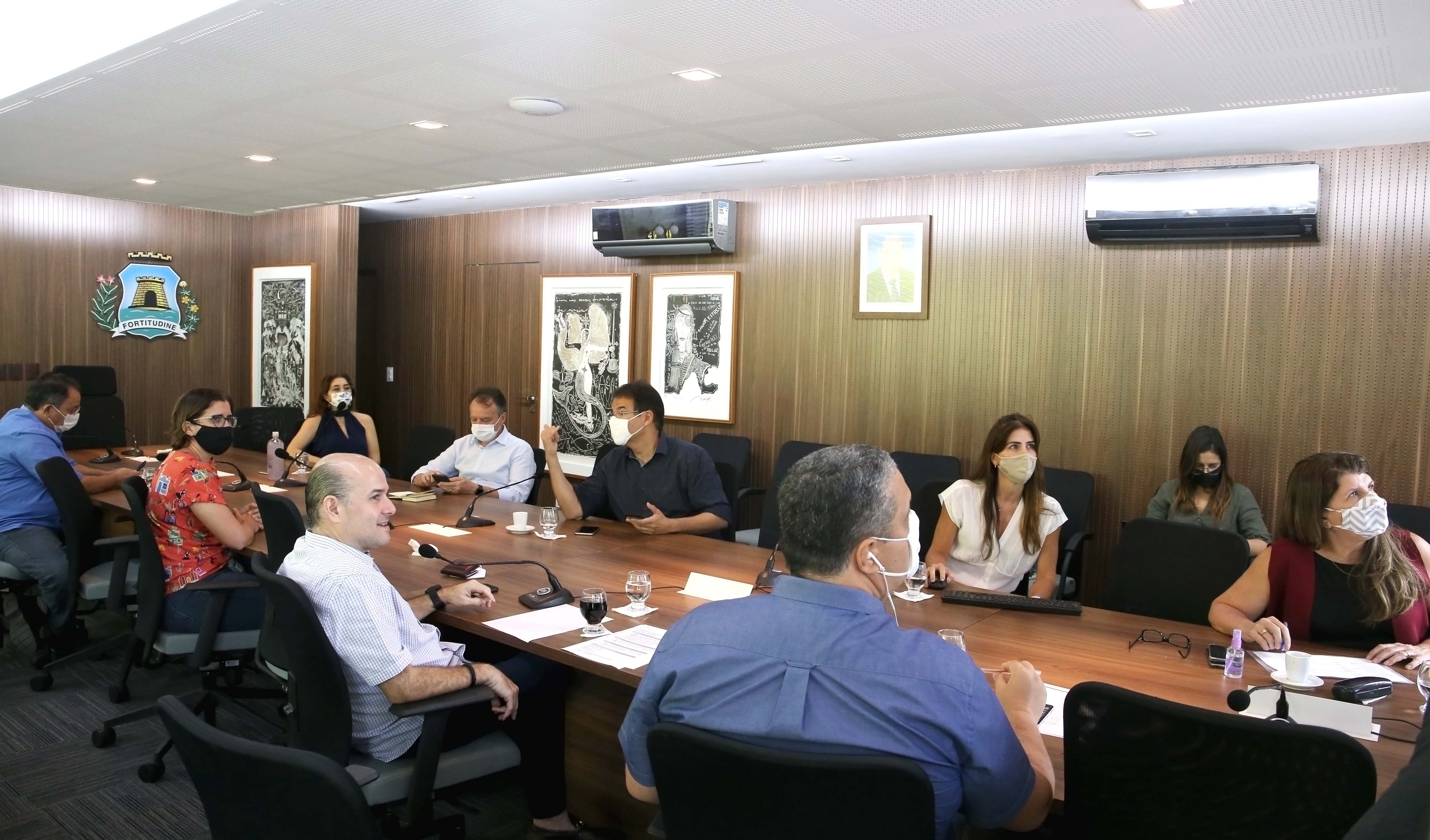 Prefeito e secretários sentados ao redor de mesa conversando